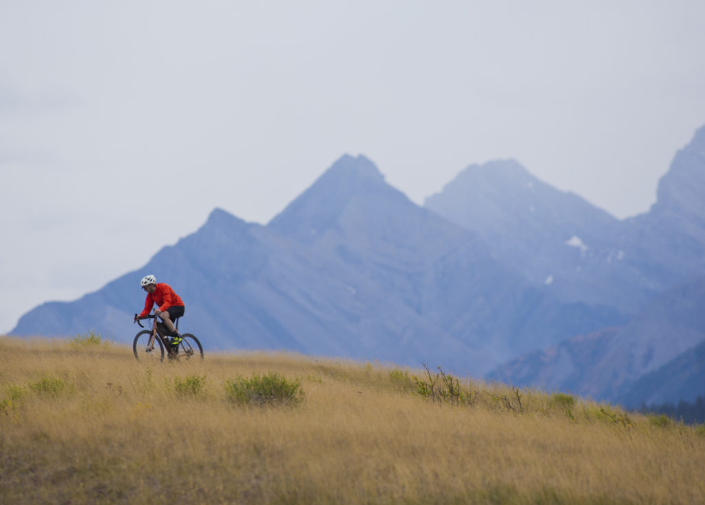 Biking on a hill top with mountain peaks in the background in Kananaskis Country.